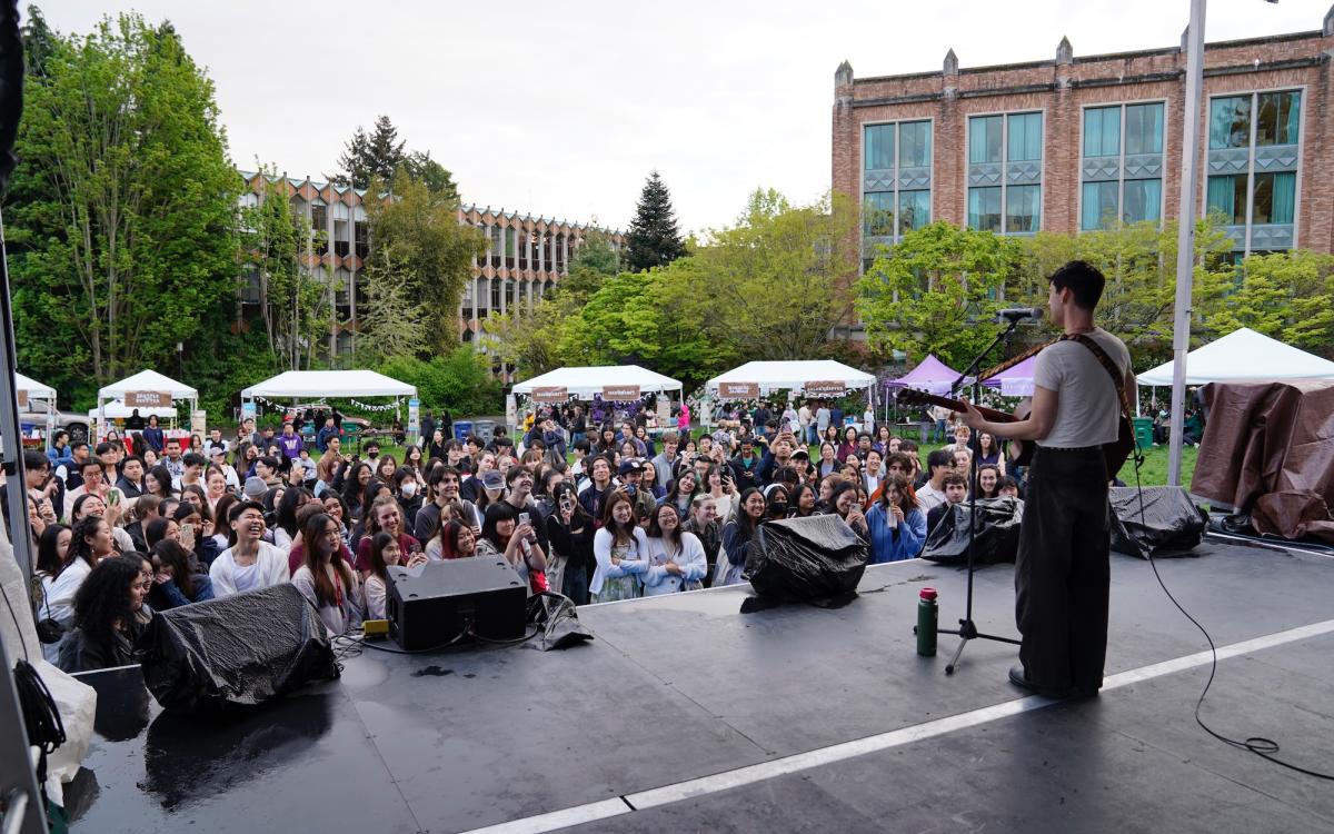 Musician standing on stage facing crowd of people 