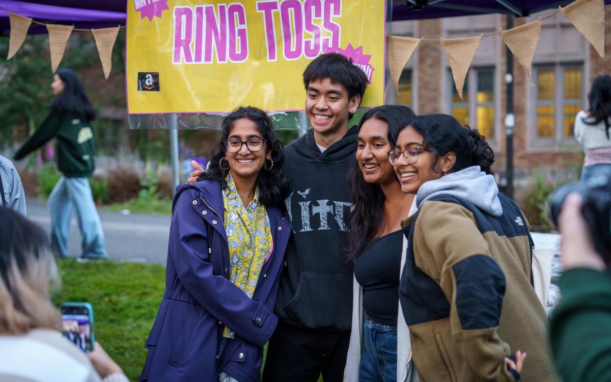 Three students hugging and taking picture with musician