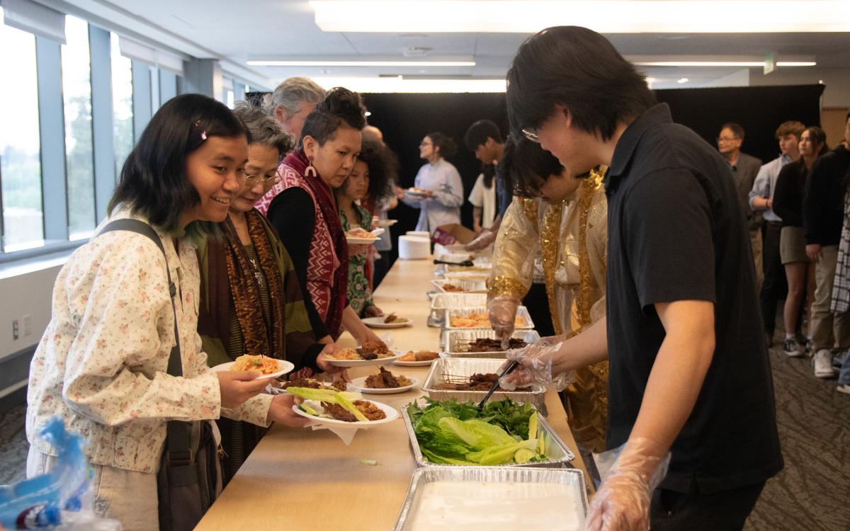 Folks grabbing food from a food line 