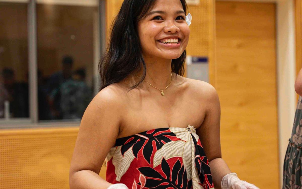 A smiling Hui member serves Hawaiian food.