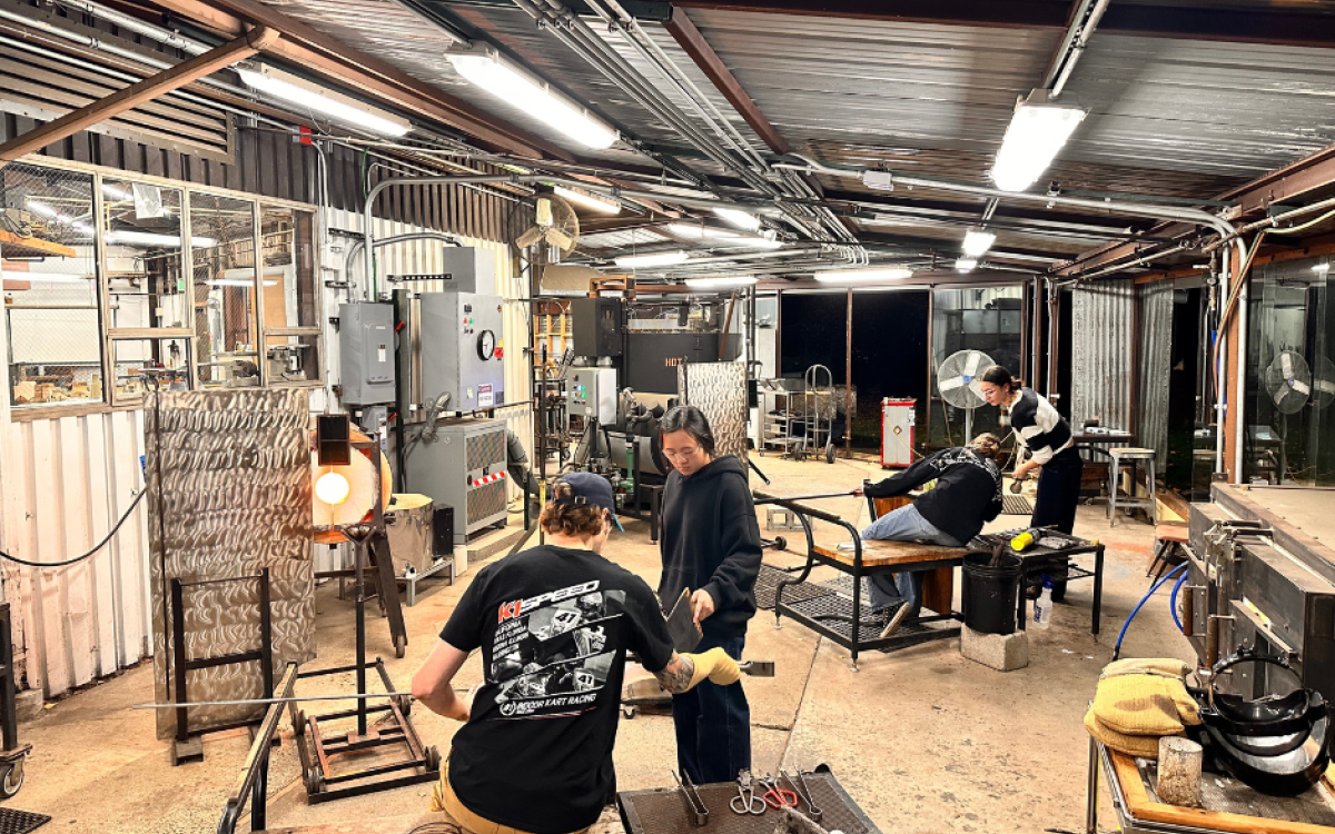 A photo of undergraduate students blowing glass in our hot glass studio at the University of Washington. 
