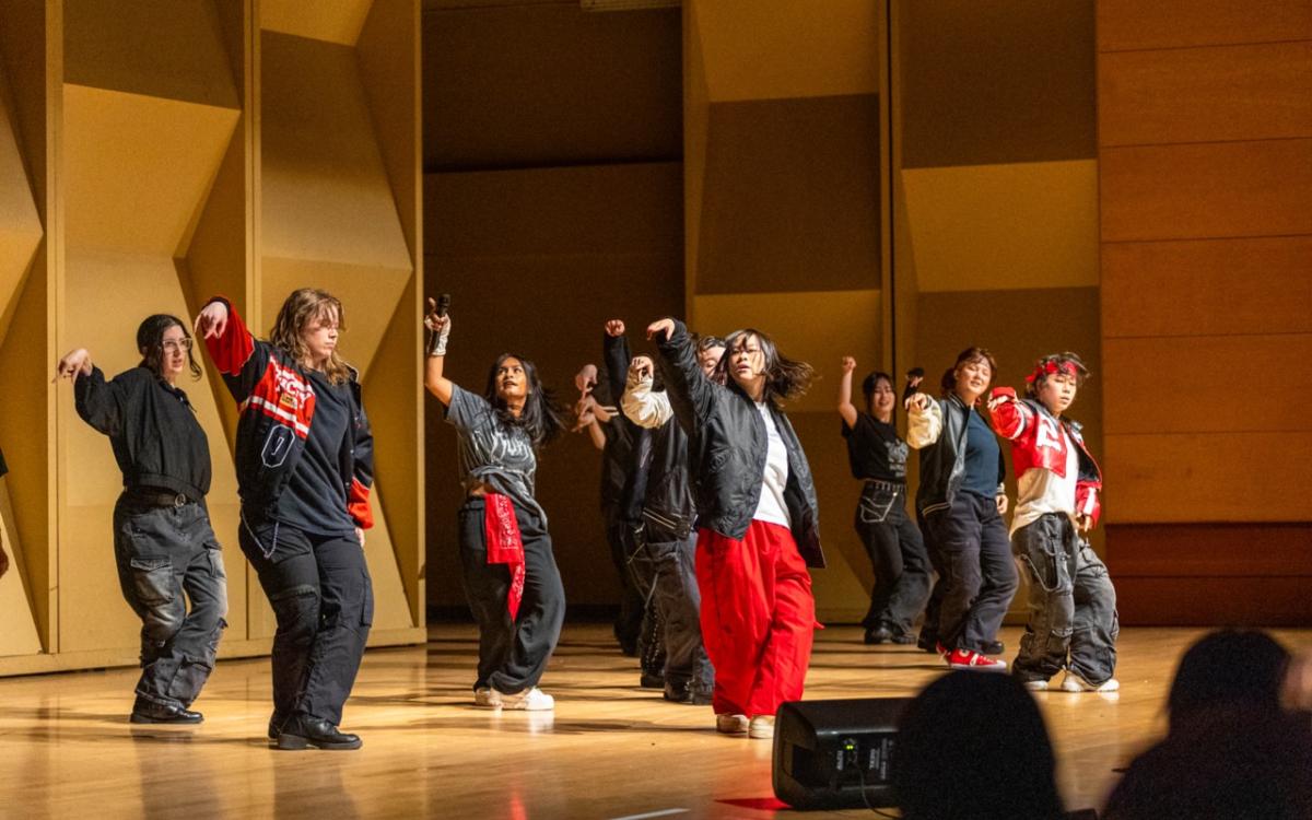 Group of dancers in black and red outfits dancing.