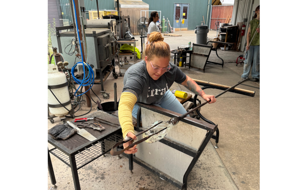 A photo of Skye OBrien blowing glass at the University of Washington hot glass art shop